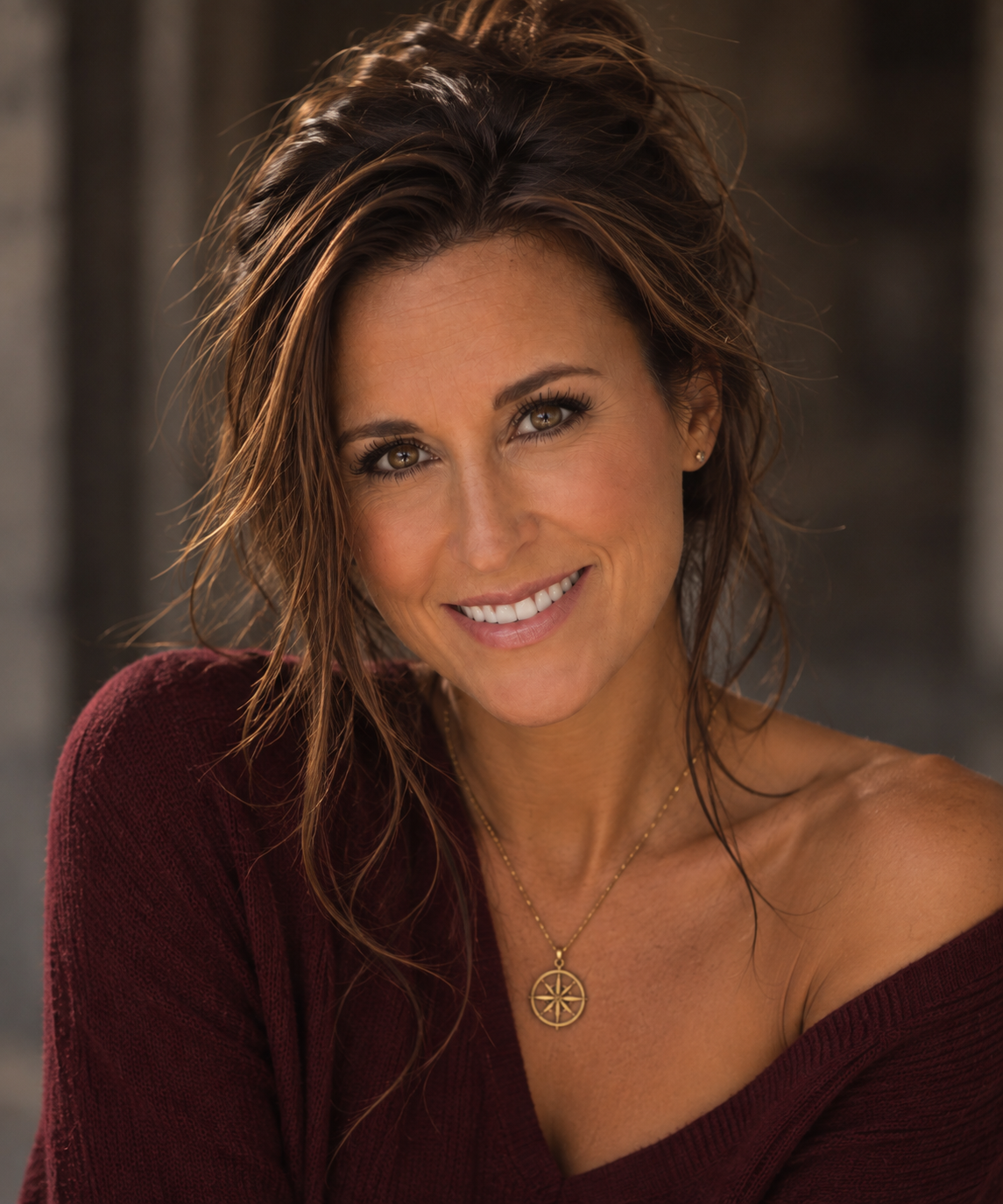 Portrait of Lore Lassen in a burgundy sweater, smiling in warm afternoon light